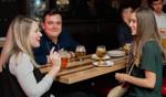 University of Guelph alumni enjoying a social event, with two smiling individuals engaged in conversation, set in an indoor venue with a casual atmosphere.