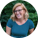 A professional portrait of Dr. Kristina Kupferschmidt, B.Eng '14, PhD '25, a woman with shoulder-length blonde hair, wearing glasses and a blue and black striped top, smiling outdoors with green foliage in the background.