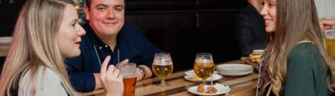 University of Guelph alumni enjoying a social event, with two smiling individuals engaged in conversation, set in an indoor venue with a casual atmosphere.
