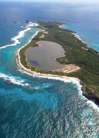 Aerial view of a lush island in the Lesser Antilles, surrounded by turquoise waters and white sandy beaches.