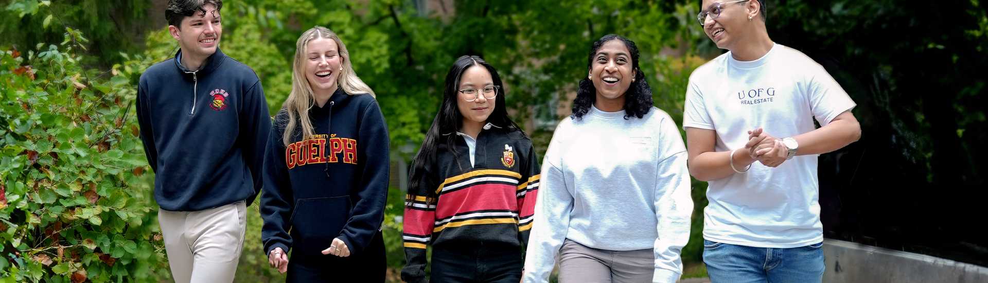 Five University of Guelph students walking outdoors on campus, smiling and wearing U of G branded apparel, featured in a web banner for Giving Tuesday.