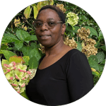 Dr. Melerin Madekufamba, a University of Guelph alum, posing outdoors with green foliage in the background.