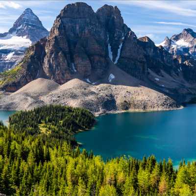 Nature scene with trees and lake in foreground and snowy mountains in background